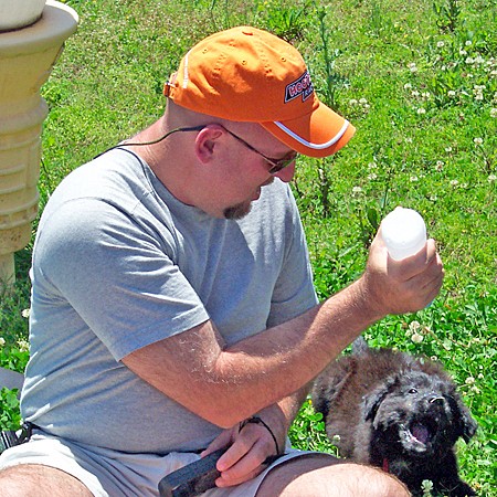 Jim is squirting Destin with water from a water bottle at a roadside rest stop.